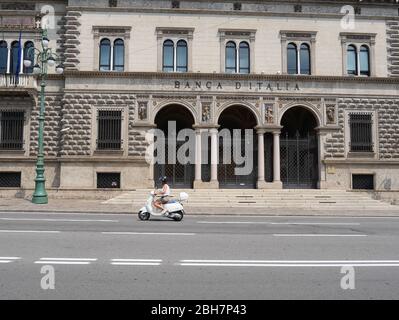 Bergamo, Italien - 06. August 2019: Ein Mädchen fährt einen weißen Vespa Roller vor einem geschlossenen Bankgebäude Stockfoto