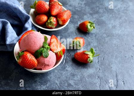 Eiskugel mit frischen Erdbeeren in Schüssel auf blauem Stein Hintergrund mit freiem Text Raum. Leckeres kaltes Dessert im Sommer. Stockfoto