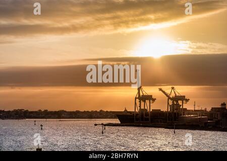 Silhouetten von Schiffen und Kränen im Melbourn Port bei Sonnenuntergang, Australien Stockfoto