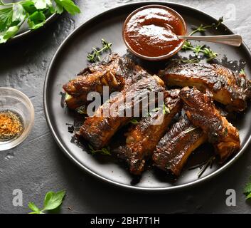 Nahaufnahme von gegrillte Spareribs auf die Platte über der schwarzen Stein Hintergrund. Leckere bbq-Fleisch. Stockfoto