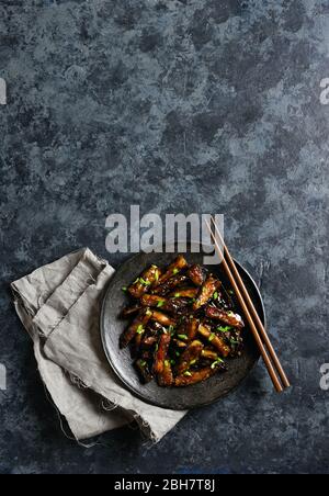 Rührbraten Bulgogi Aubergine auf Platte über dunklem Steinhintergrund mit freiem Textraum. Gebratene Aubergine im koreanischen Stil. Draufsicht, flaches Lay Stockfoto