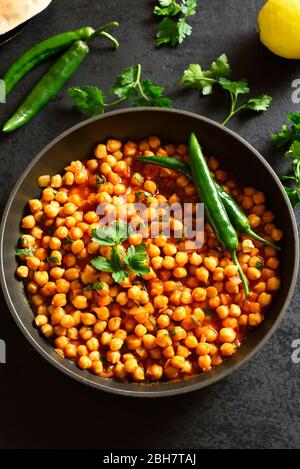 Knusprig geröstete Kichererbsen. Gericht im indischen Stil über schwarzem Stein Hintergrund. Vegetarisches veganes Food Konzept. Stockfoto