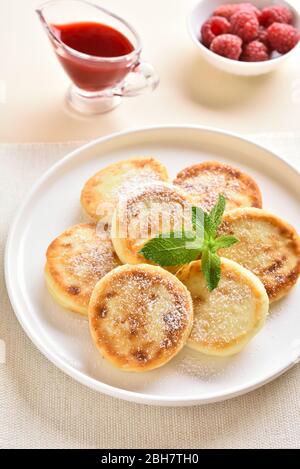 Nahaufnahme von Käsekuchen mit frischen Himbeeren auf dem Teller über hellem Steingrund. Stockfoto