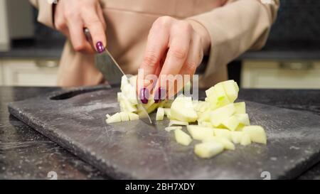 Erfahrene Hausfrau mit schönen Maniküre schneidet Gemüse Kochgeschirr zum Mittagessen in der Küche Marmortisch close-up Stockfoto