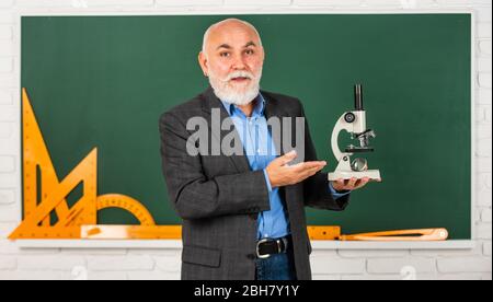 Heilung entdecken. Wissenschaftliche Experimente im Labor. Biologie Schule Laborausrüstung. Mann im Klassenzimmer mit mathematischen Werkzeugen an der Tafel. Senior Lehrer verwenden Mikroskop. Chemie im Schullabor. Stockfoto