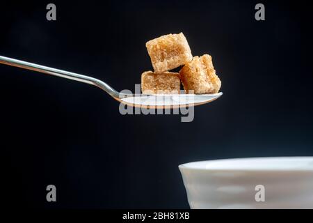 Löffel mit Würfel von braunem Demerara Zucker Stockfoto