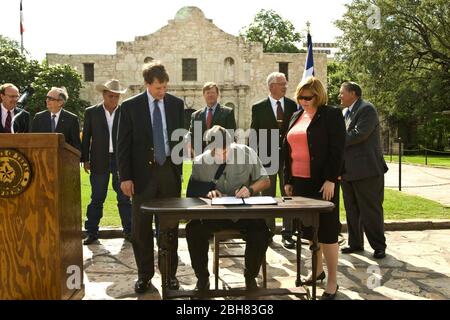 San Antonio Texas USA, 15.. Juni 2009: Der Gouverneur von Texas, Rick Perry, unterzeichnet während einer Zeremonie vor der Alamo ein Gesetz zum Schutz der Eigentümer von Immobilien in Texas. Perrys rechter Arm ist in einer Schlinge, nachdem er bei einem Fahrradunfall sein Schlüsselbein gebrochen hat. ©Marjorie Kamys Cotera/Bob Daemmrich Photography Stockfoto