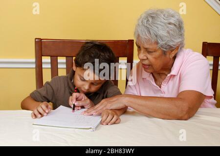 Austin, Texas USA, 22. August 2009: Fünfjähriger mexikanisch-amerikanischer Junge, der zu Hause schreibt, während seine Großmutter zuschaut und hilft. HERR ©Bob Daemmrich Stockfoto