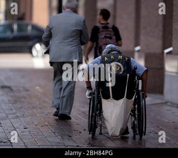 Austin Texas USA, 10 2010. März: Ein Mann im Rollstuhl, der eine Weste mit Army-Insignien trägt, schiebt sich auf den Bürgersteig im Geschäftsviertel der Congress Avenue in der Innenstadt. © Bob Daemmrich Stockfoto