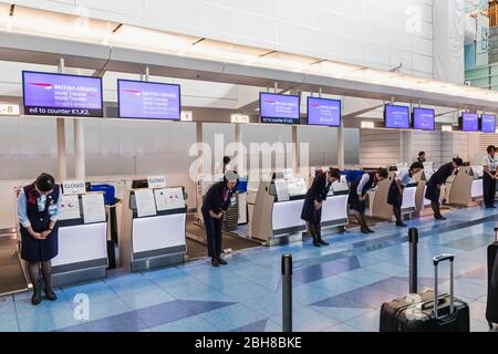 Japan, Honshu, Tokio, Flughafen Haneda, internationales Terminal, Abflugbereich, Mitarbeiter von British Airways beugen sich vor dem Öffnen der Check-in-Schalter vor den Kunden Stockfoto