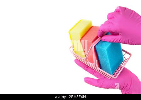 Miniatur-Warenkorb mit Waschschwämmen, die von weiblichen Händen gehalten werden und rosa Einweghandschuhe tragen. Isoliert auf weißem Kopierplatz. Stockfoto