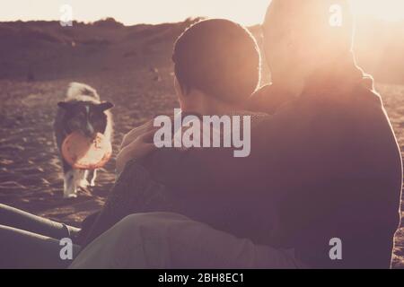 Schöne Szene mit Paar kaukasischen Mann und Frau umarmt mit Liebe am Strand und schöne Hund Grenze Collie gehen zu ihnen mit einem Spiel fragen, um zusammen für immer in der Familie Freizeit zu spielen Stockfoto