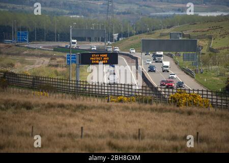 Cumbernauld, Großbritannien. April 2020. Im Bild: Straßenschilder entlang der Autobahn M80, die lauteten: „BLEIB ZUHAUSE, SCHÜTZE NHS, RETTE LEBEN“ die britische Regierung hat eine längere Stillegungen aller großen Städte Großbritanniens angeordnet und die Menschen zu Hause bleiben lassen, obwohl einige Leute die Botschaft der Regierung ignorieren wollen. Bis heute hat die Coronavirus (COVID-19) Pandemie weltweit über 2.74 Millionen Menschen infiziert, und in Großbritannien 143,464 infiziert und 19,506 getötet. Quelle: Colin Fisher/Alamy Live News Stockfoto