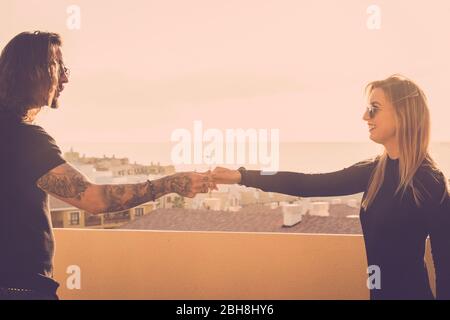 Nette kaukasische junge Paar von Menschen Mann und Frau tanzen auf dem Dach mit herrlichem Blick auf die Stadt und die Küste mit Meer im Hintergrund. Sonnenuntergang golde Licht und Vintage-Stil Stockfoto