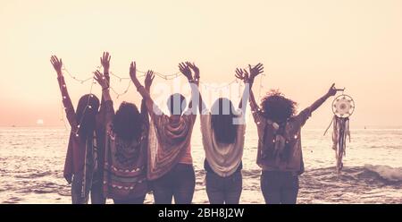 Vintage Tones Bilder von fünf Frauen Freunde von hinten gesehen aufgeben Hände für Glück vor einem Sonnenuntergang auf dem Meer und halten Lichter und ein Traumfänger für spirituelle Konzept Stockfoto