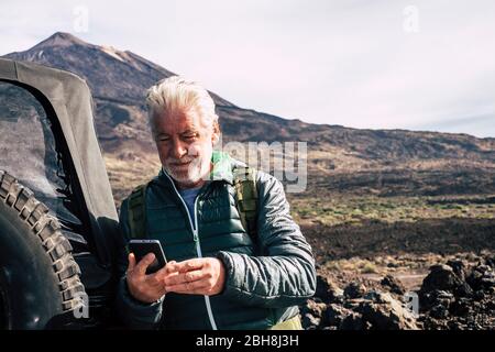 Kaukasischen alten Mann verwenden moderne Technologie Handy am Berg während Urlaub mit Geländewagen am Berg - Planung von Karten und Straßen genießen die Natur im Freien für alternative Urlaub mit Abenteuer Stockfoto