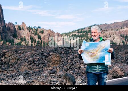 Weiße Haare alten erwachsenen Mann suchen und überprüfen Sie eine Papierkarte auf der Straße eines Wander-und alternative Freizeitaktivitäten oder Urlaub in den Bergen - Menschen genießen die Umwelt im Freien Stockfoto