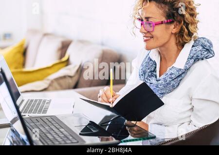 Junge schöne Geschäftsfrau Lächeln und arbeiten mit zwei verschiedenen Laptop - moderne alternative Büro zu Hause für unabhängige Menschen - Sekretärin und Business Manager Konzept Stockfoto