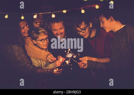 Nacht Party Feier wie Silvester 2019 oder chsristams für kaukasische große moderne Familie mit funkelt Licht Feuerwerk zusammen in Freundschaft Spaß haben - Menschen lächeln und feiern mit verschiedenen Altersgruppen und Generationen Stockfoto