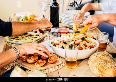 Gruppe von kaukasischen Freunden genießen zusammen ein glückliches Mittagessen mit italienischem Fleisch lke Pasta und Pizza - Bier und Wein, um Freude an der Freundschaft haben - Holztisch - Home Restaurant Konzept Stockfoto