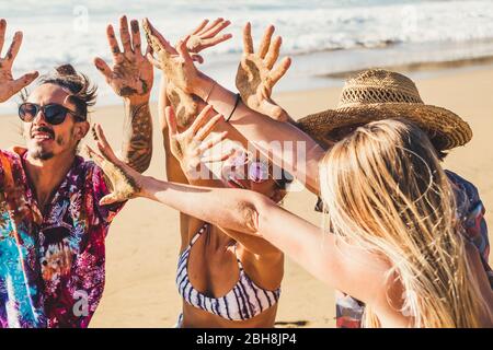 Freunde Menschen im Sommerurlaub am Strand zeigen sich nach einem lustigen Tag voller Aktivitäten am Meer Lifestyle mit den Händen zusammen Sandboden - Gruppenmänner und -Frauen genießen die Sonne gemeinsam in Freundschaft Stockfoto