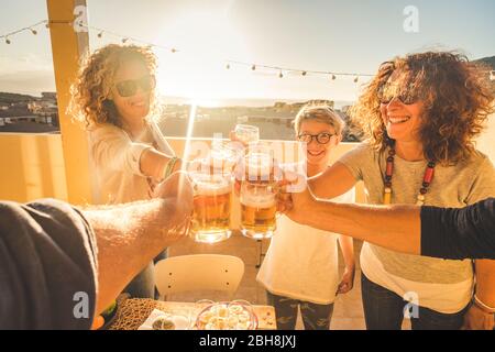 Gruppe von Freunden zusammenklimmen Spaß in Freundschaft im Freien auf der Dachterrasse mit Stadt und Meerblick während des Sommers Abendessen bei Sonnenuntergang zu Hause - Urlaub und Lifestyle genießen Stockfoto