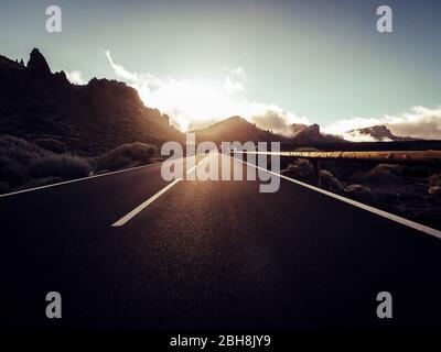 Lange Straße am Berg mit vulkan-Montierung vor und blauem, klarem Himmel - Bodensicht mit schwarzem Asphalt und weißen Linien - Fahr- und Reisekonzept Stockfoto