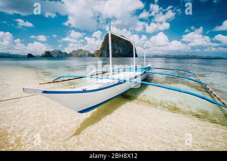 White banca Boot am Sandstrand bereit für Inselhüpffahrt. Erstaunliche Pinagbuyutan Insel im Hintergrund. Schöne Landschaft in El Nido, Palawan, Philippinen. Stockfoto