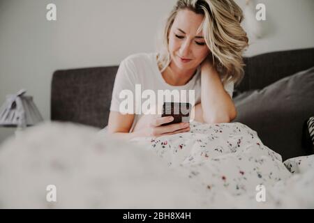 Frau mit Smartphone im Bett Stockfoto