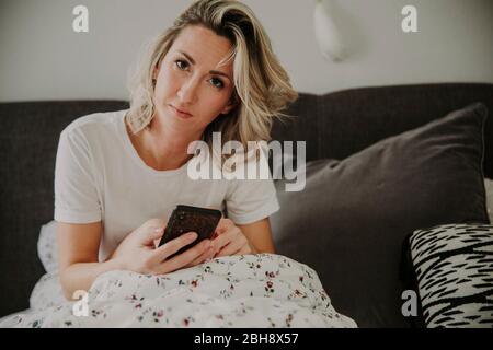 Frau mit Smartphone im Bett Stockfoto