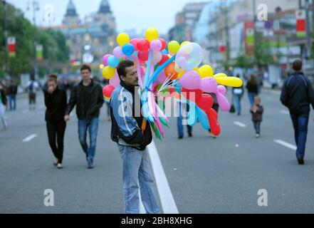 Trauriger Mann, Verkäufer, der bunte Ballons verkauft, die mitten auf der Straße stehen Stockfoto