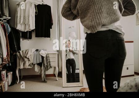 Frau steht vor dem Spiegel, bekleidet Stockfoto