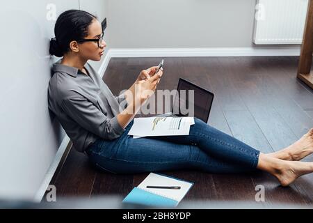 Geschäftsfrau mit Smartphone im Wohnzimmer Stockfoto
