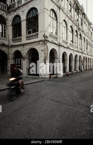 Gegend um das Oriental Hotel mit alten Kolonialgebäuden und Moped Riders Stockfoto