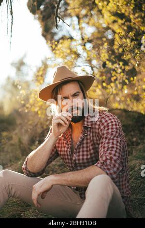 Junger Mann mit Bart und Hut auf einem schönen Sonnenuntergang in den Bergen Stockfoto