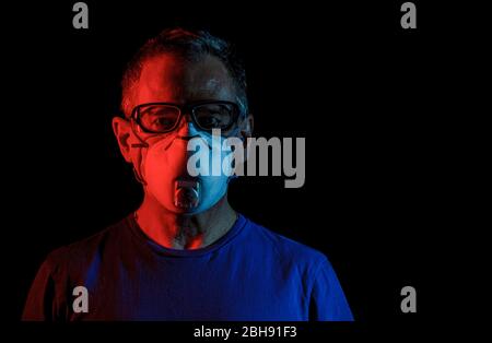 Ein älterer Mann, der eine Maske und eine Schutzbrille trägt Stockfoto