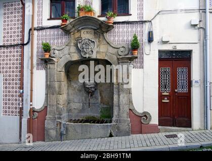 Ein öffentlicher Trinkbrunnen, einmal die örtliche Wasserversorgung, in die Vorderseite eines Hauses in Porto, Portugal gebaut Stockfoto