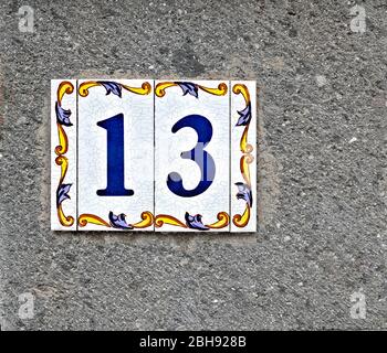 13, Nummer dreizehn, dekorative Fliesenarbeiten auf grauer Oberfläche. Stockfoto