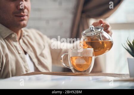 Fokussierter Mann, der eine Teekanne in der Hand hält Stockfoto