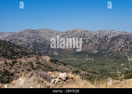 Felsige Berge und Täler mit Olivenbäumen und verschiedenen Vegetation. Sonniger Tag mit blauem Himmel im Herbst. Zentralkreta, Griechenland. Stockfoto