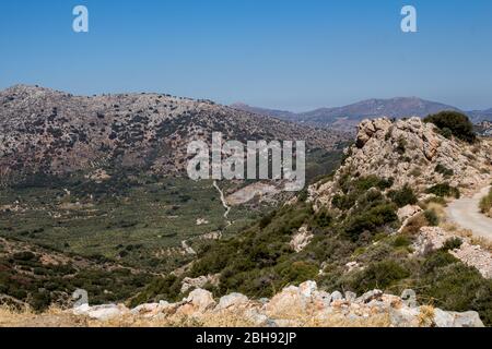 Felsige Berge und Täler mit Olivenbäumen und verschiedenen Vegetation. Sonniger Tag mit blauem Himmel im Herbst. Zentralkreta, Griechenland. Stockfoto