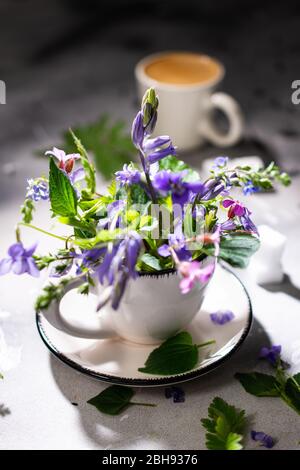 Feldblumen auf einem alten Tisch mit einer Tasse Kaffee.Morgen Espresso.leckeres Getränk und Essen. Stockfoto