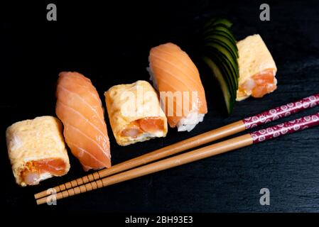 Nigiri-Sushi aus japanischer Küche auf schwarzem Teller mit Wasabi und Sojasoße. Sushi Roll mit Lachs, Sushi Maki Roll und Tamago Sushi auf schwarzem pla Stockfoto