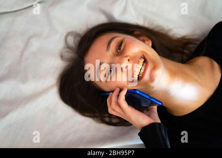 Frau am Telefon im Bett. Stockfoto