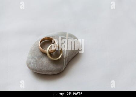 Eheringe auf Stein mit kreuzförmigen Linien, weißer Hintergrund Stockfoto