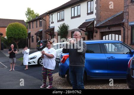 Jackfield Brass Band Cornet-Spieler Jason Pickin zollt NHS-Mitarbeitern Tribut, während seine Nachbarn klatschen, um ihre Unterstützung während der COVID-19-Pandemie zu zeigen. Stockfoto