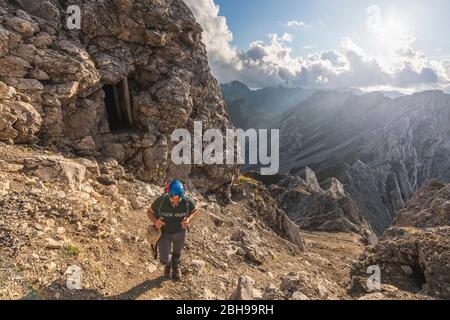 Ein Wanderer auf dem Bepi Zac Höhenweg, vorbei an einer Kriegshöhle, Costabella Ridge, Marmolada Gruppe, Dolomiten, Fassatal, Trient Provinz, Trentino-Südtirol, Italien Stockfoto