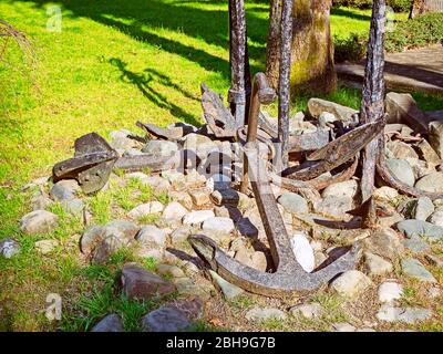 Alte Anker liegen auf den Steinen auf der Straße Stockfoto