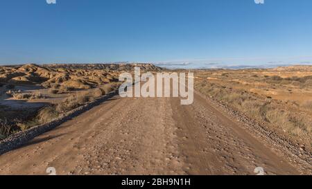 Roadtrip im Winter durch die Halbwüste Bardenas Reales, Navarra, Spanien. Ein UNESCO Biosphärenreservat mit u.a. Castil de Tierra, Pisquerra Mountains und Bardena Blanca. Schotterstraße. Stockfoto