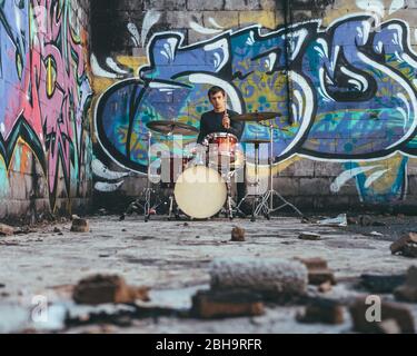 Junger Mann, der in einer unterirdischen Umgebung Schlagzeug spielt Stockfoto